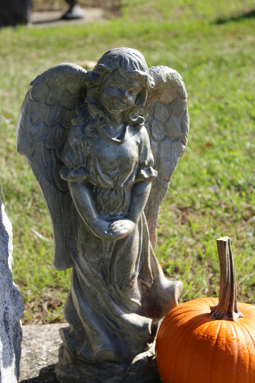 uma estátua de um anjo ao lado de uma abóbora