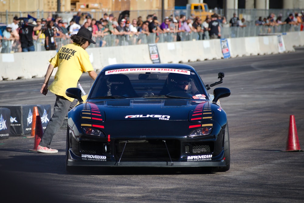 a man standing next to a car on a race track