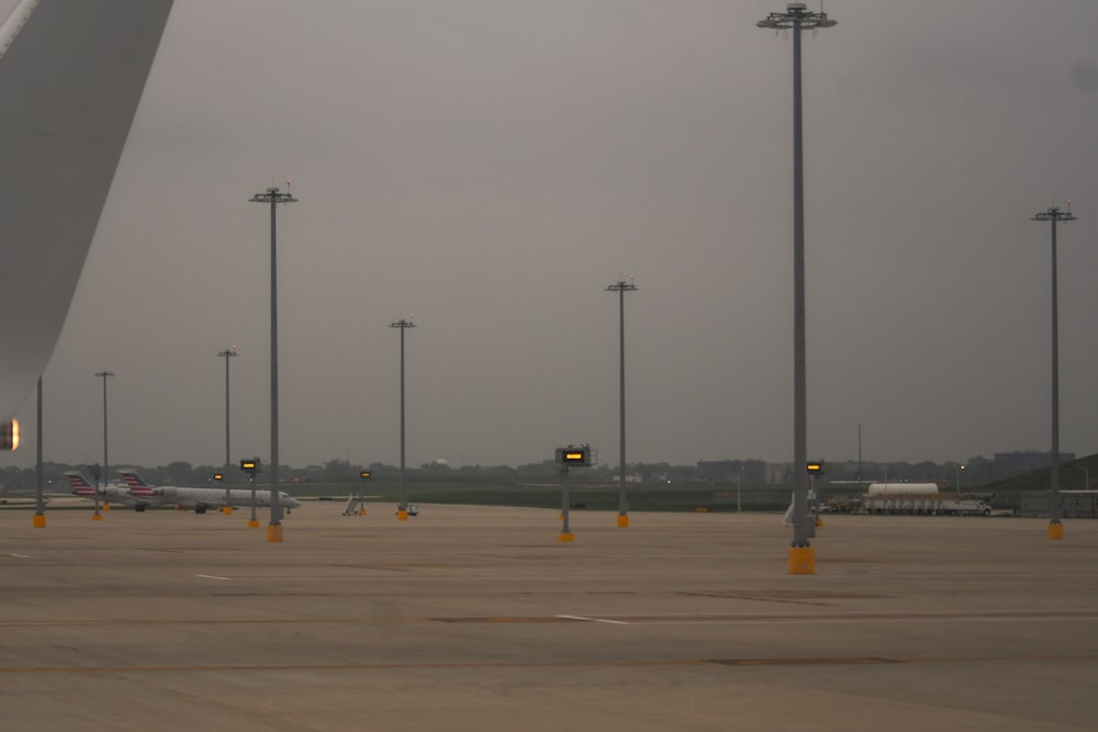 an airport tarmac with several lights and a plane in the background