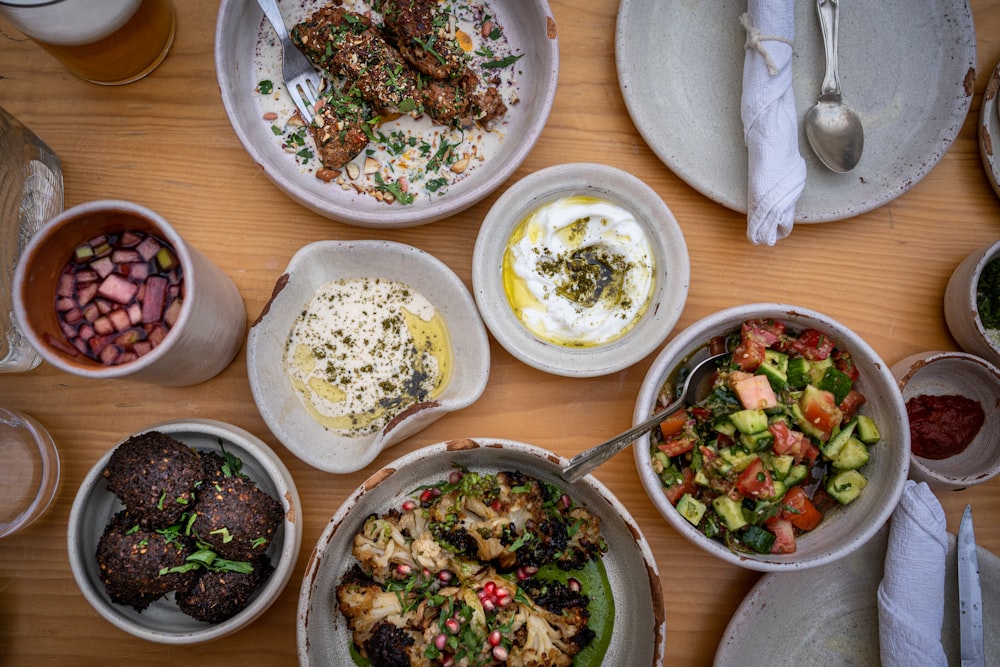 a wooden table topped with bowls of food