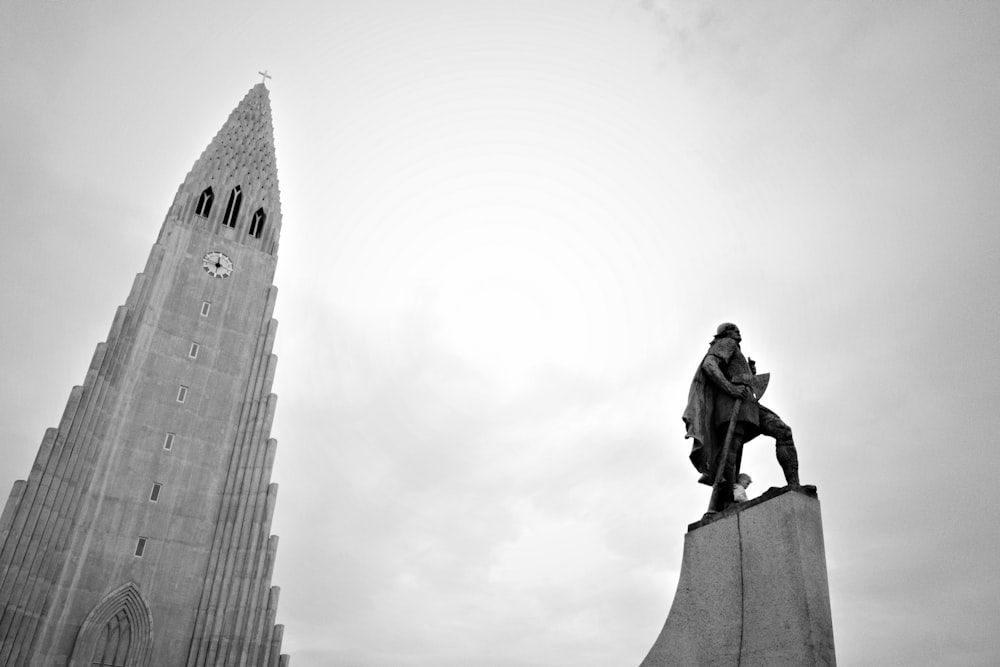 a black and white photo of a statue in front of a tall building