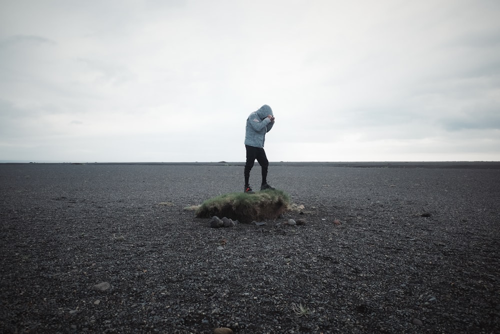 a person standing on top of a rock in the middle of a field