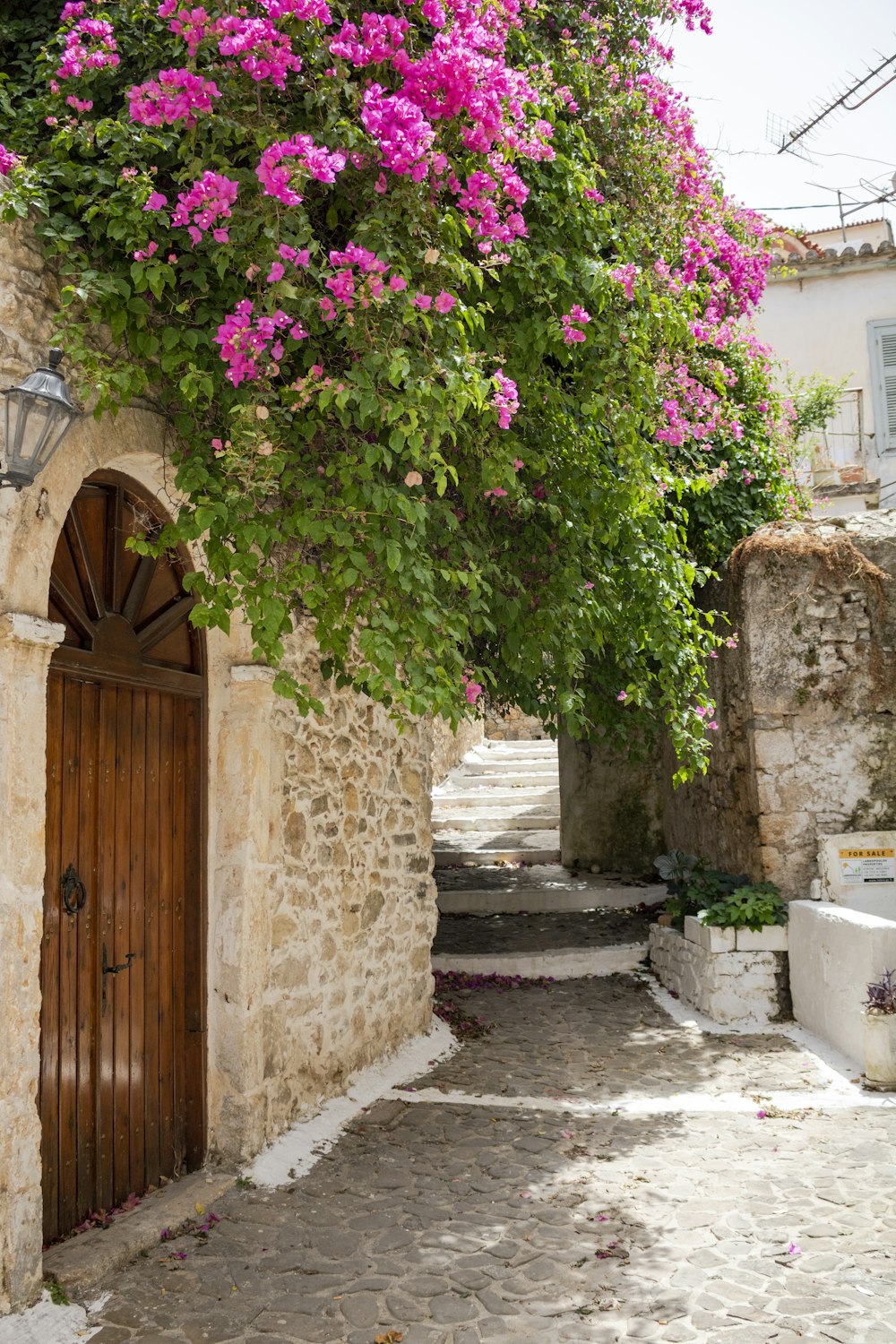 a stone building with a wooden door surrounded by pink flowers