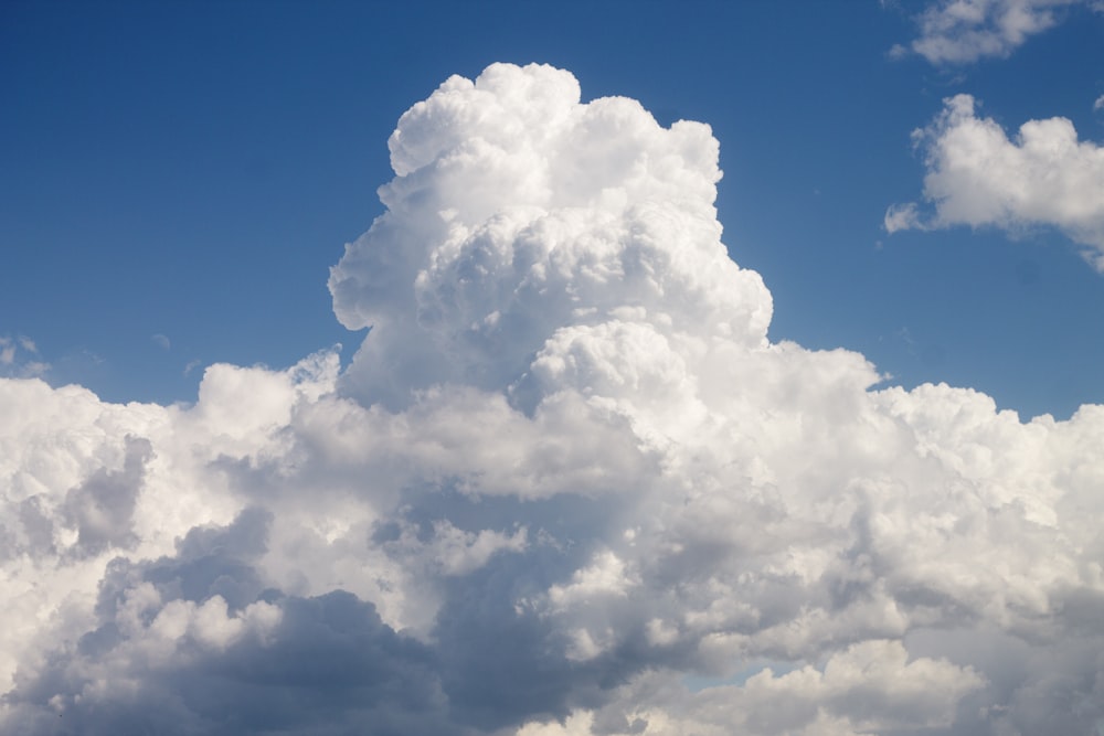 Eine große Wolke steht am Himmel über einem Feld