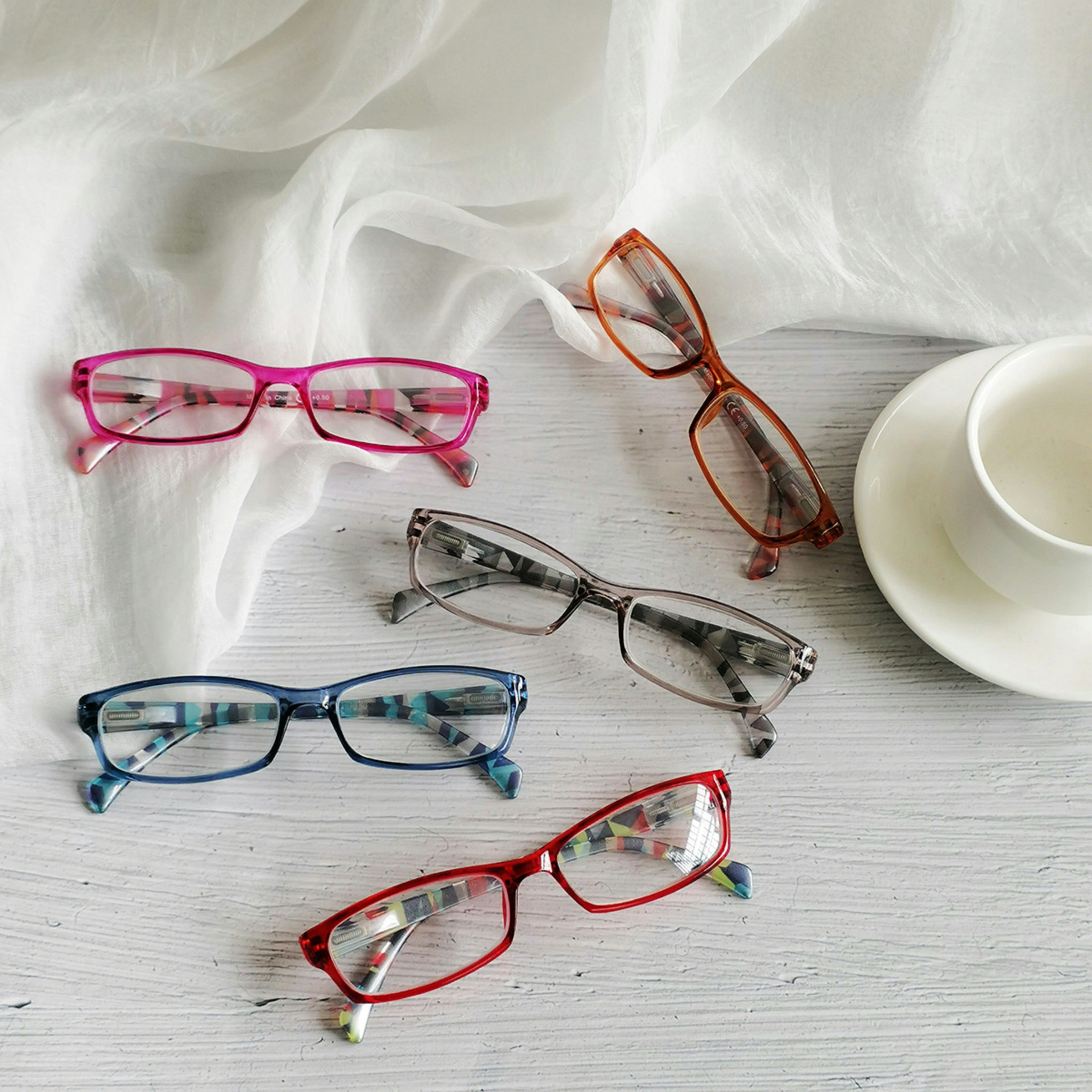 three pairs of glasses sitting next to a cup and saucer