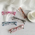 three pairs of glasses sitting next to a cup and saucer