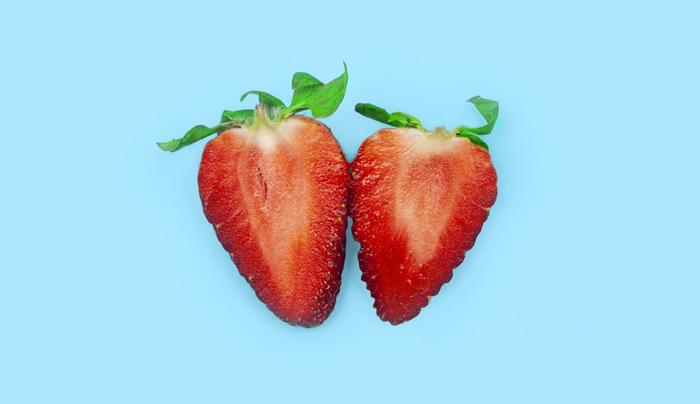 a couple of strawberries sitting on top of a blue surface