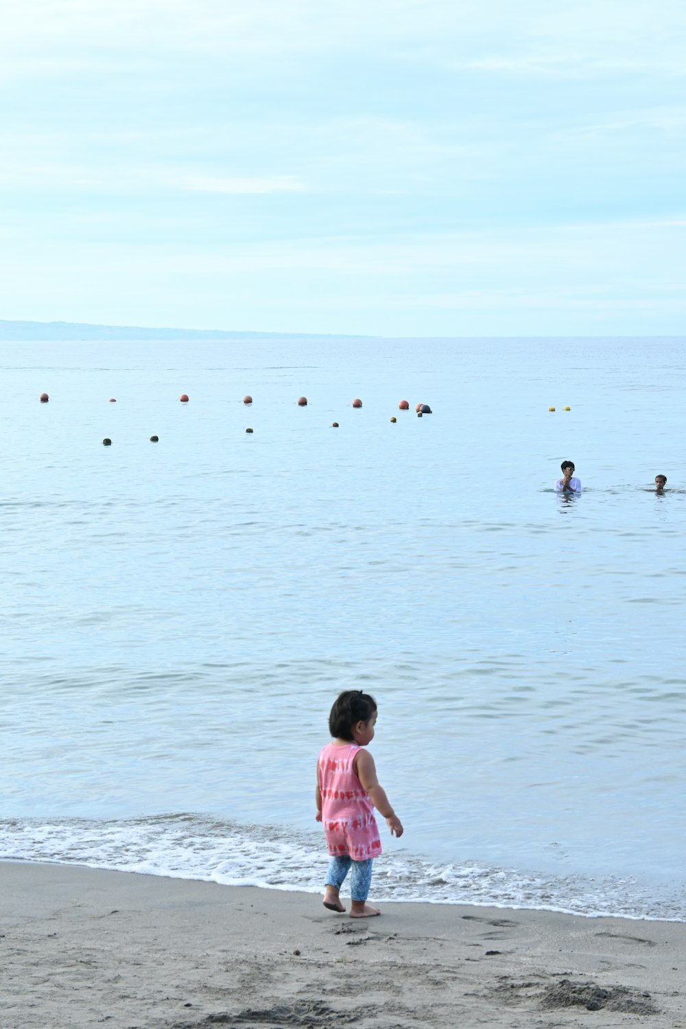 a little girl standing on top of a sandy beach