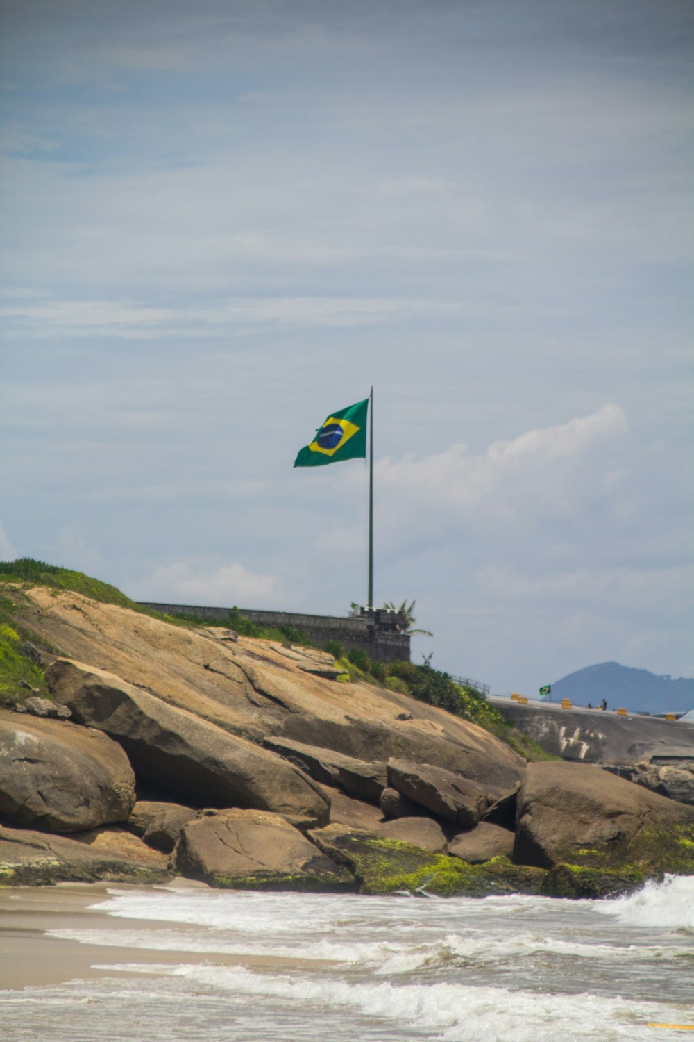 a flag flying on a rocky beach next to the ocean