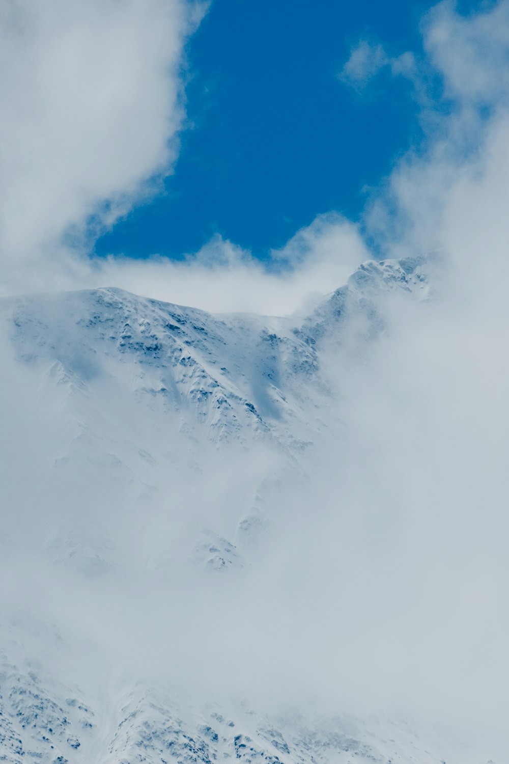 a snow covered mountain with clouds in the sky