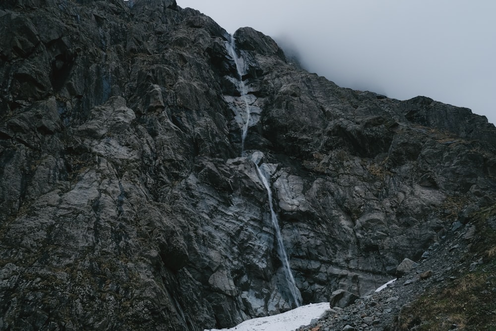 a tall mountain with a waterfall running down it's side