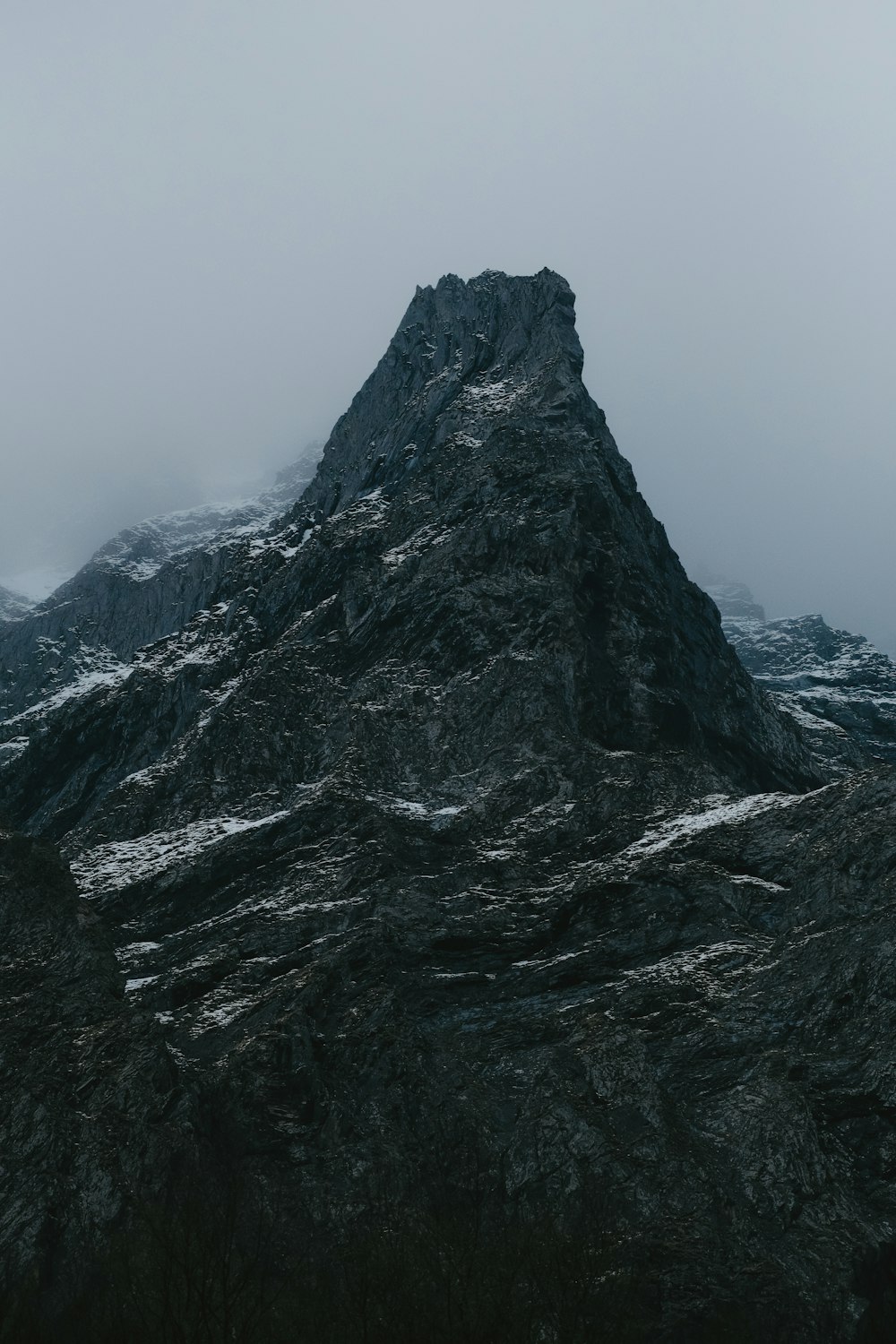 a very tall mountain in the middle of a foggy day