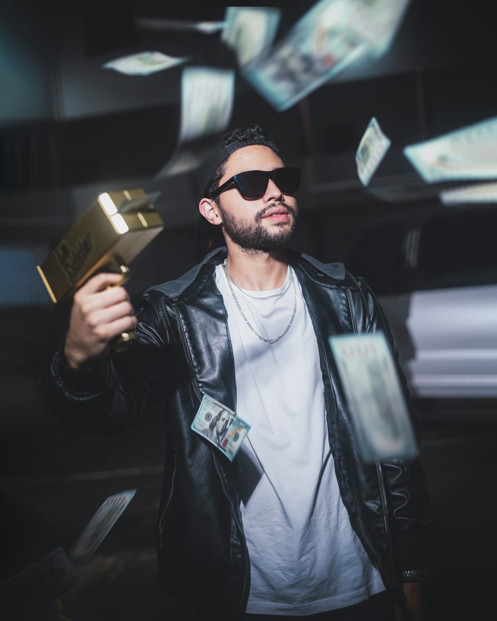 a man in a black jacket and sunglasses holding a gold object