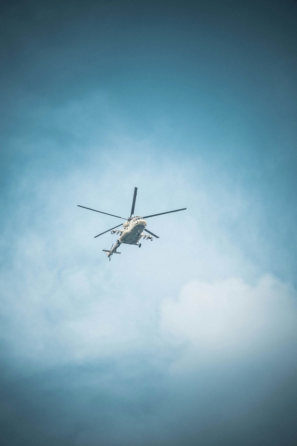 a helicopter flying through a blue cloudy sky