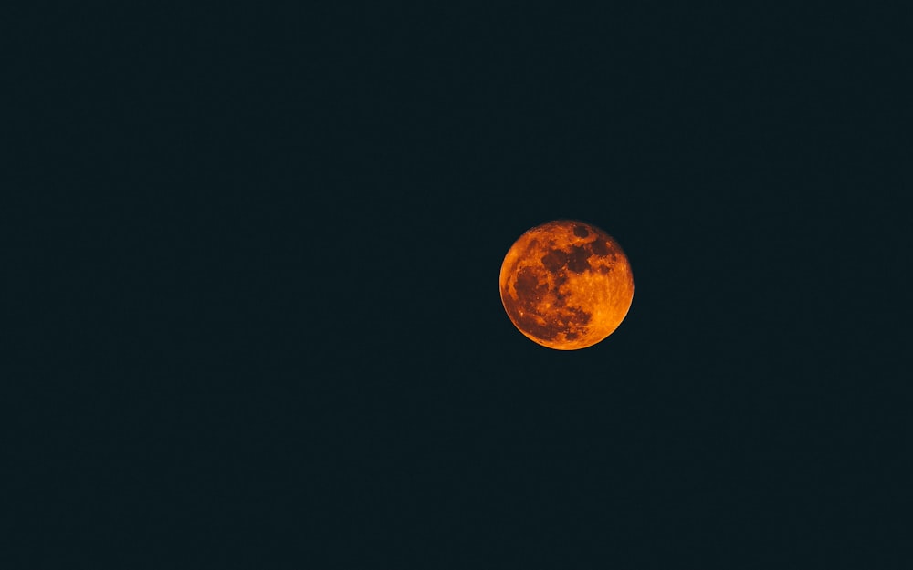 a bright orange moon in the dark sky