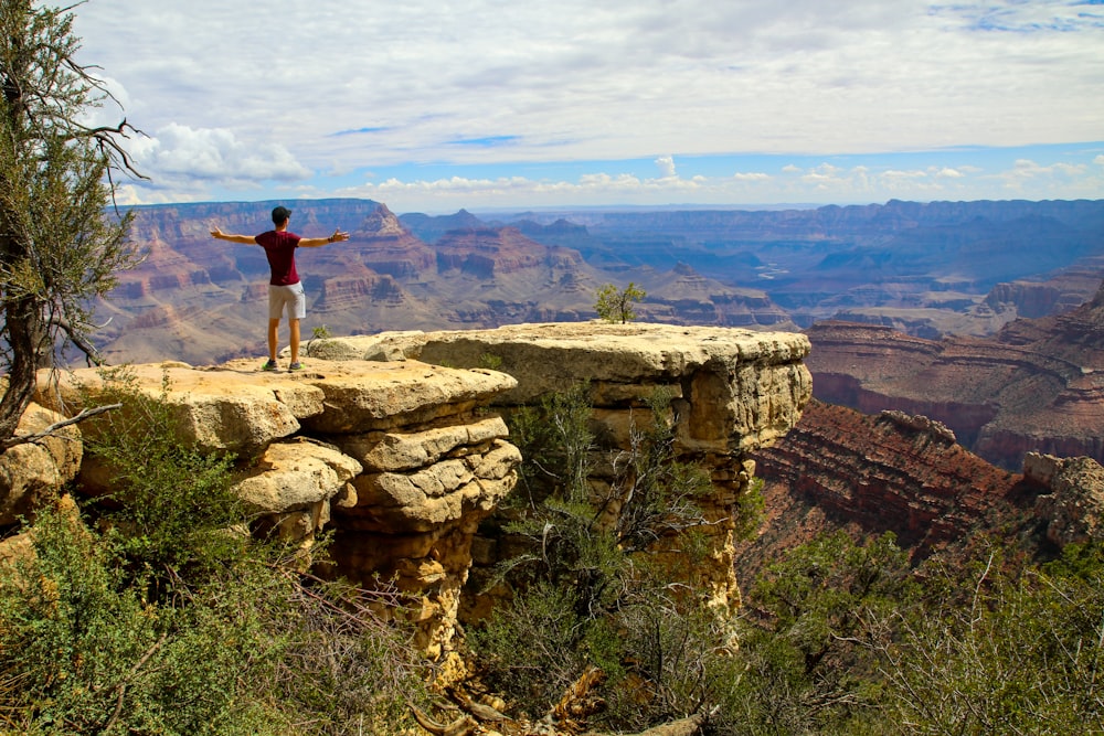Un hombre parado en la cima de un acantilado con vistas a un cañón