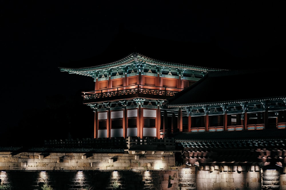 a building lit up at night with water in front of it