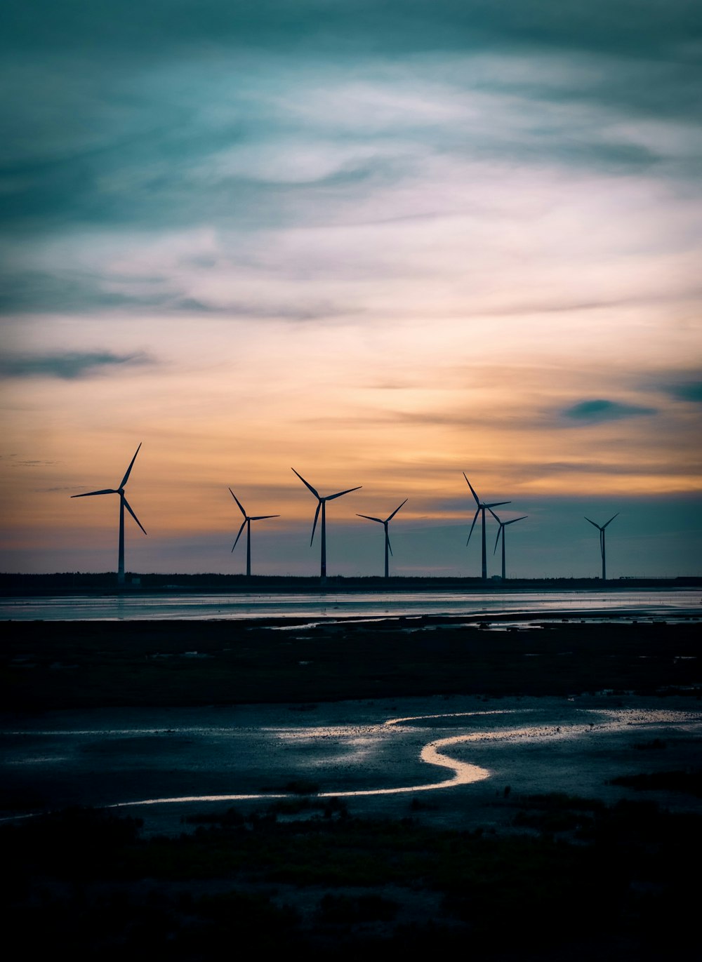 a group of windmills in the distance on a cloudy day