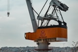 A large industrial crane with an orange base and complex metal framework towers above an urban landscape filled with densely packed buildings. The sky is overcast, giving the scene a muted lighting effect. The name 'Haliç Tersanesi' is prominently displayed on the crane.