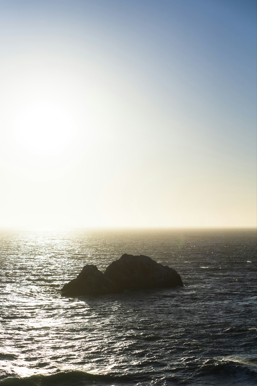 a large body of water with a small rock in the middle of it