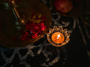 An elegant candle nestled among rich fabrics and delicate floral accents, glowing softly.