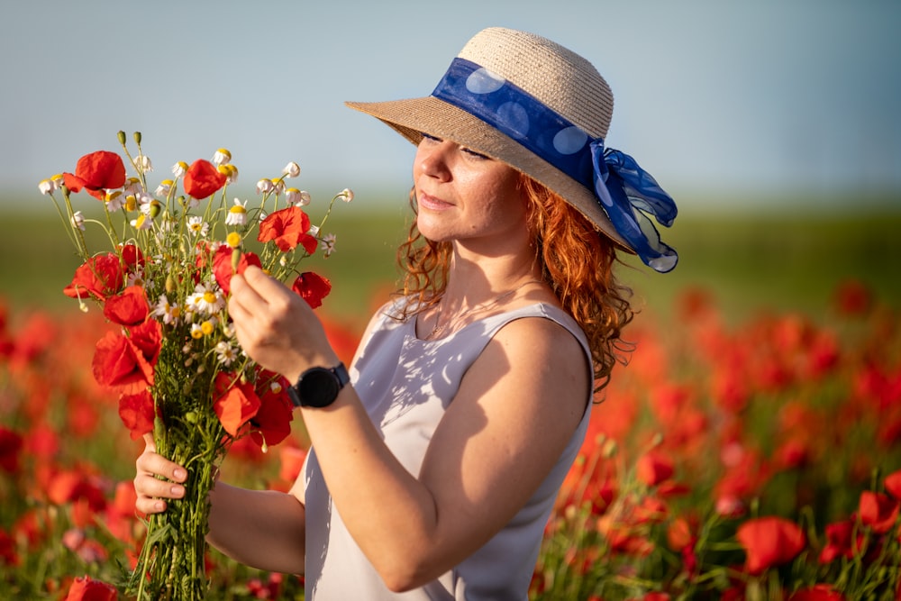 Foto Una mujer con sombrero sosteniendo un ramo de flores – Imagen Persona  gratis en Unsplash