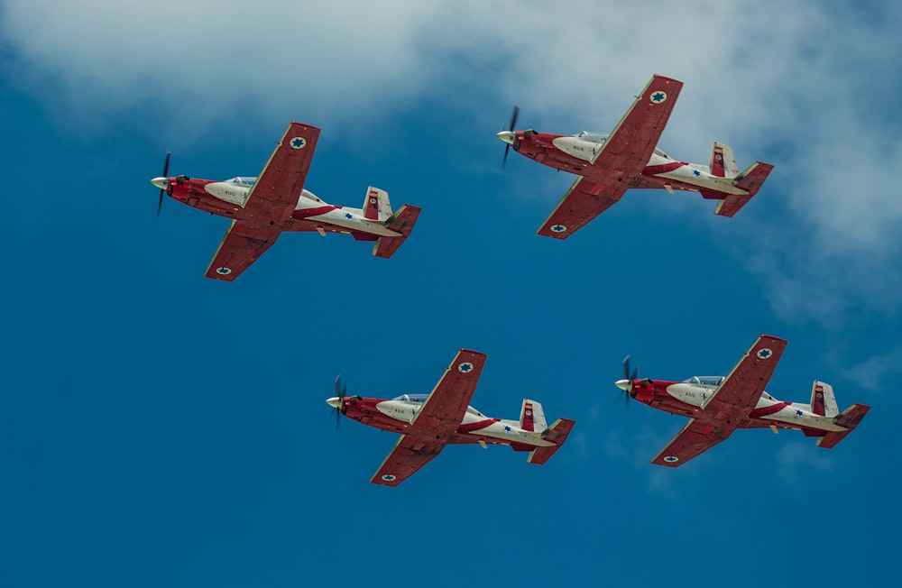 three red and white airplanes flying in formation