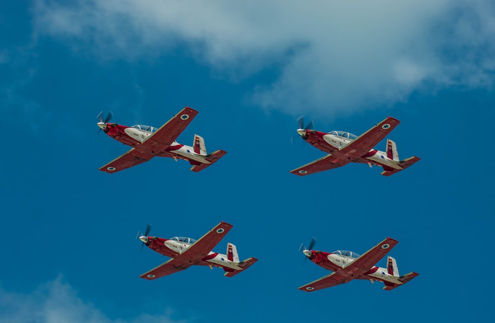 four red and white airplanes flying in formation