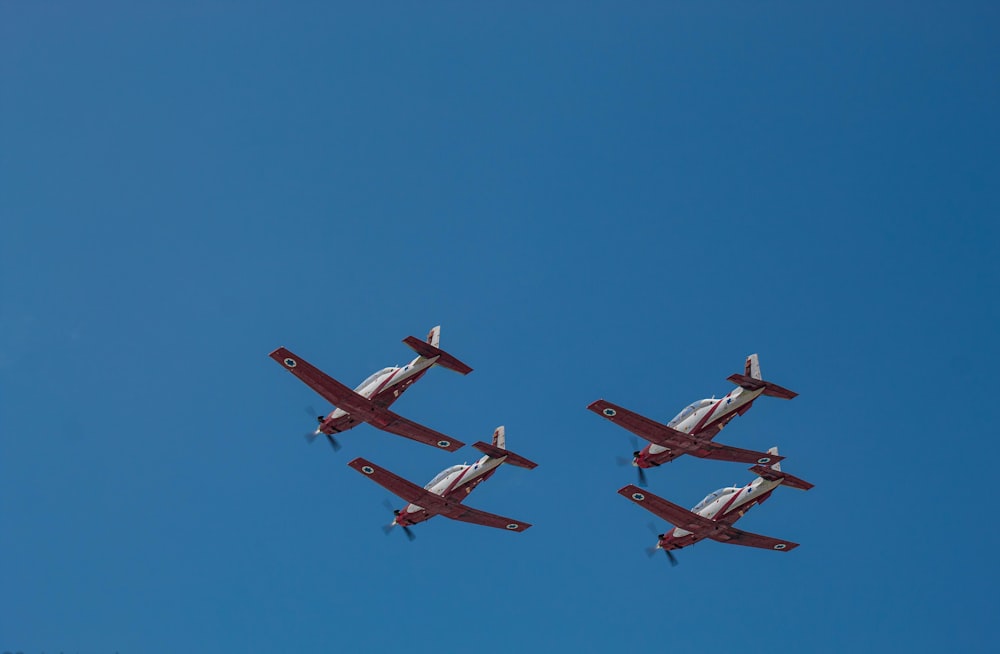 three red and white airplanes flying in the sky