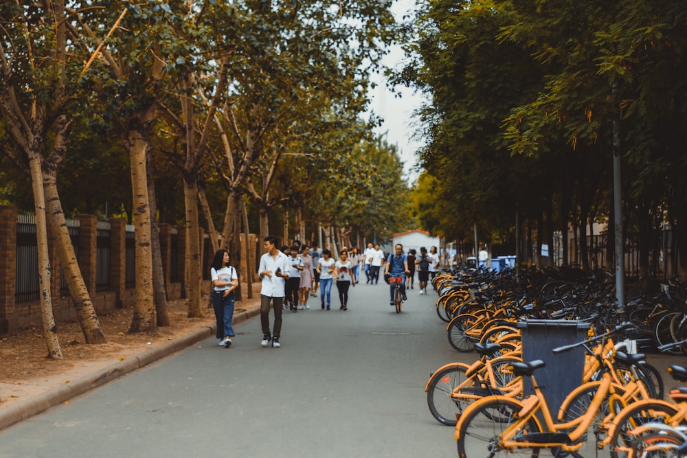 a group of people walking down a street next to parked bikes