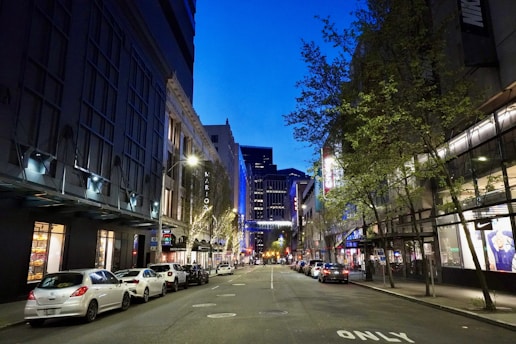a city street at night with cars parked on both sides