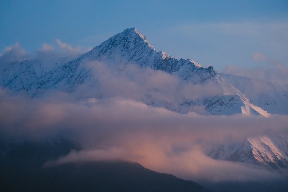 a mountain covered in clouds and a blue sky