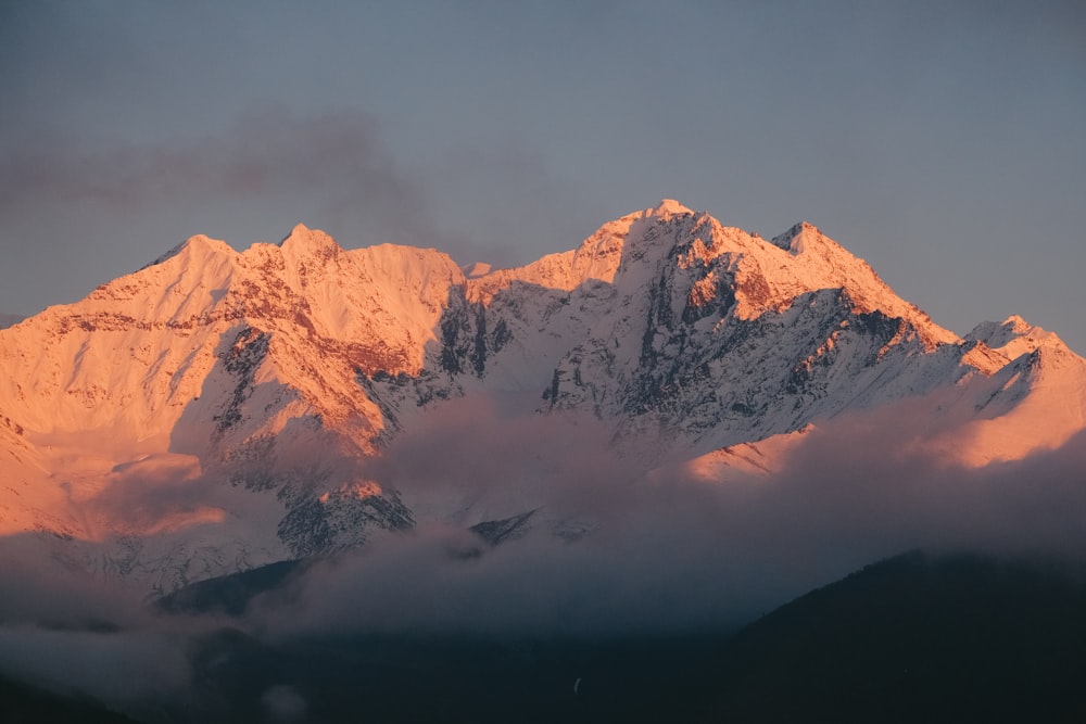 a snow covered mountain with clouds in the foreground