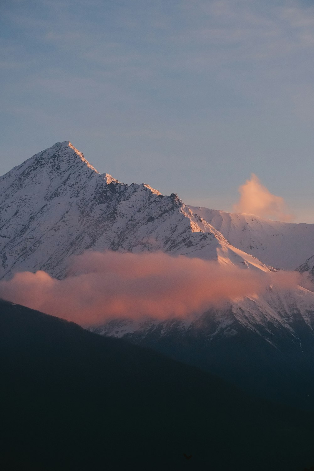 a snow covered mountain with clouds in the foreground