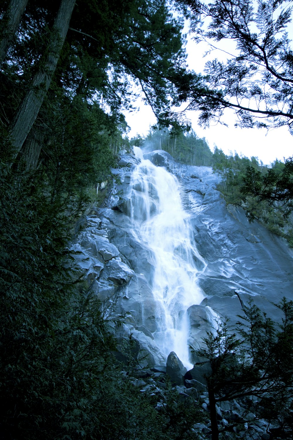 a very tall waterfall in the middle of a forest