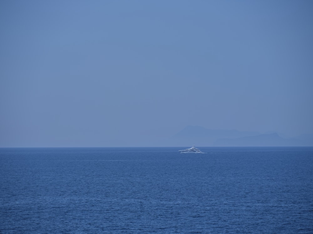 a boat in the middle of the ocean on a clear day