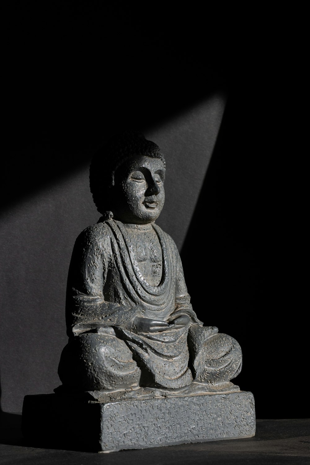 Una statua di Buddha seduta in cima a un blocco di cemento