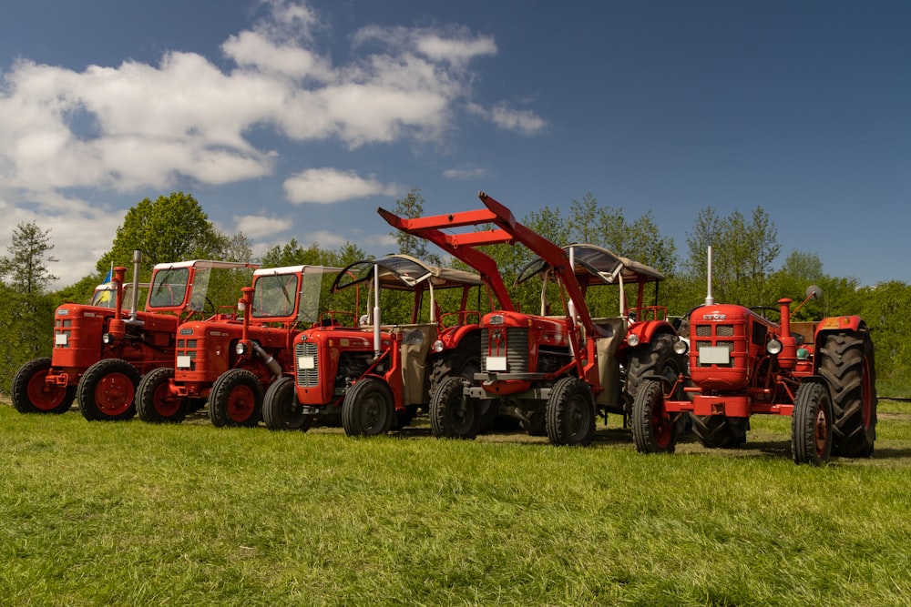 a row of red farm tractors parked in a field