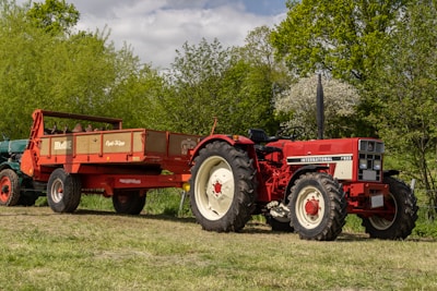 a red tractor pulling a trailer behind it