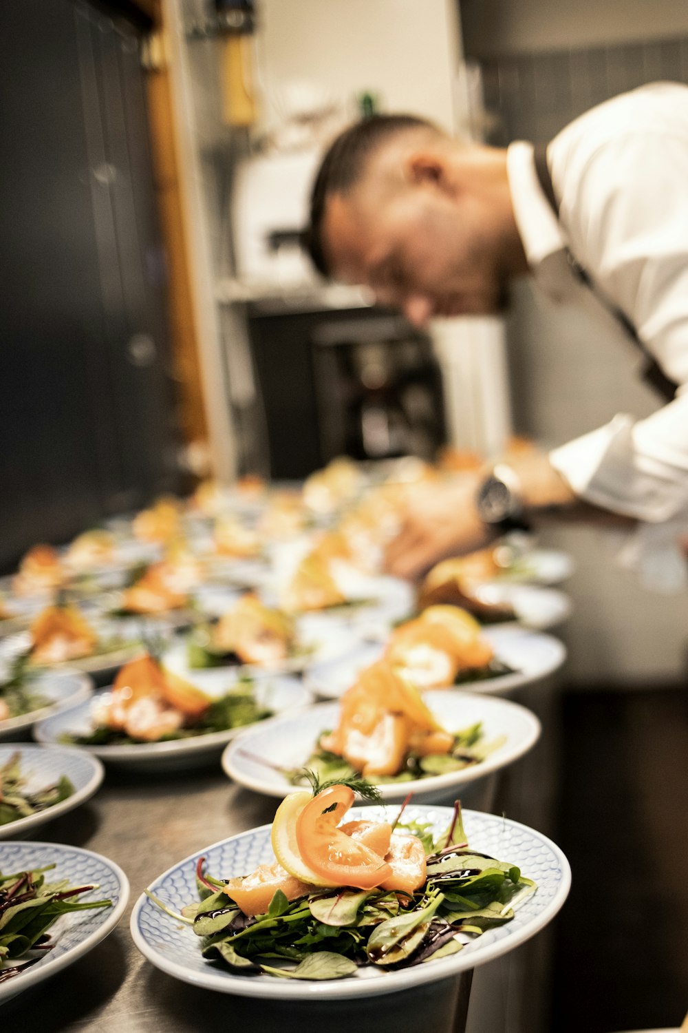 a chef preparing food on plates in a kitchen