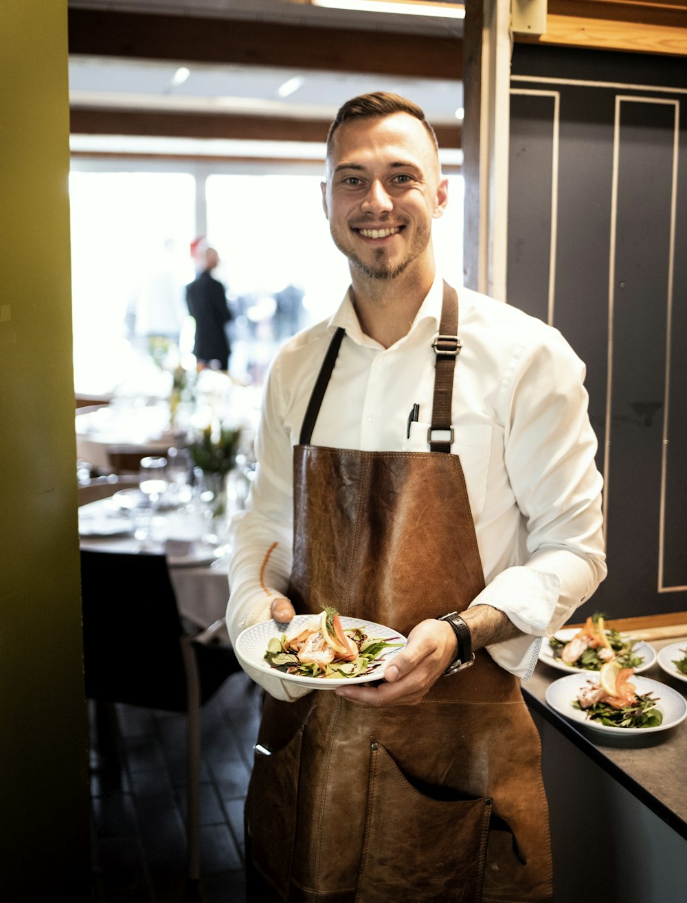 a man in an apron holding a plate of food