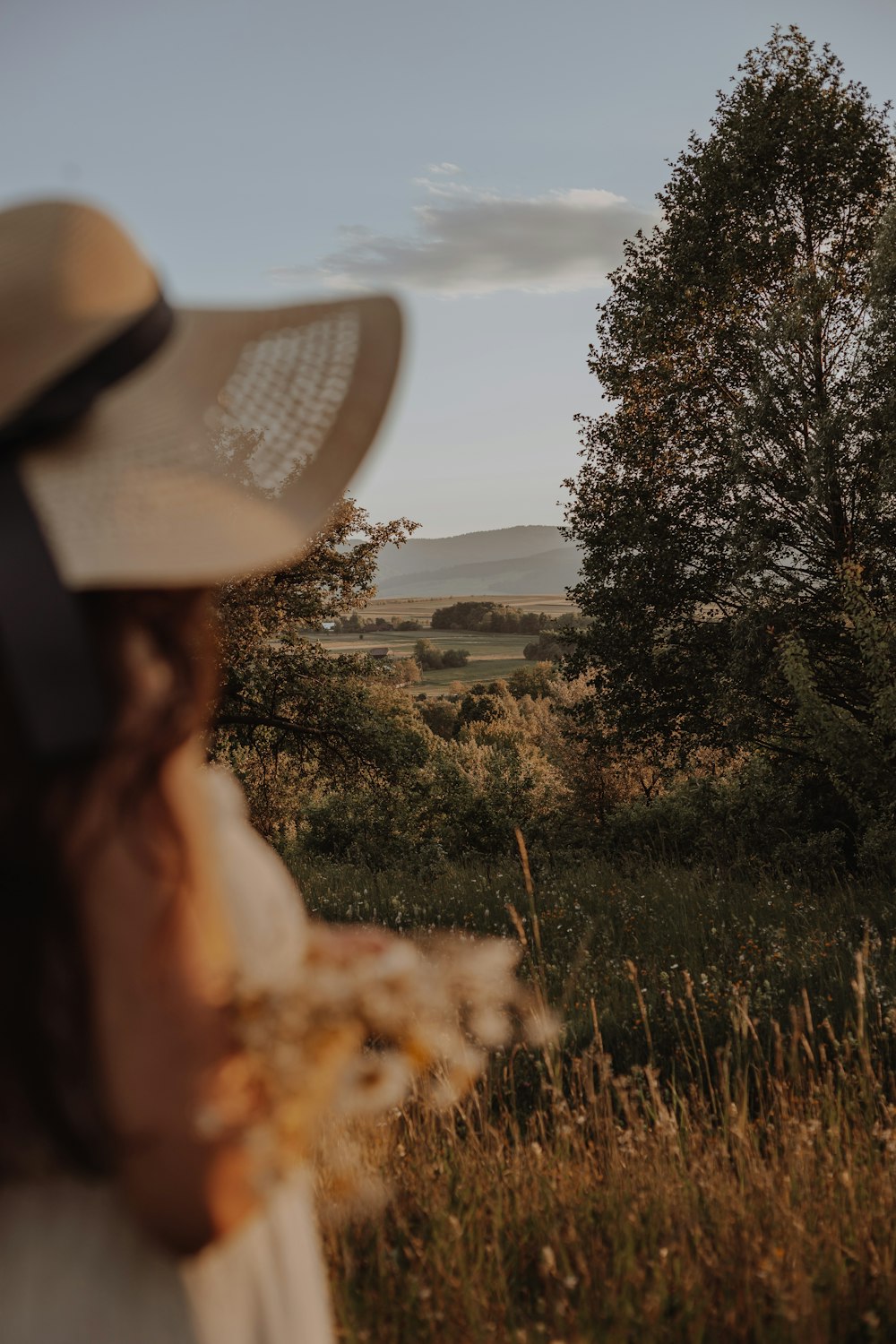 a woman wearing a hat standing in a field