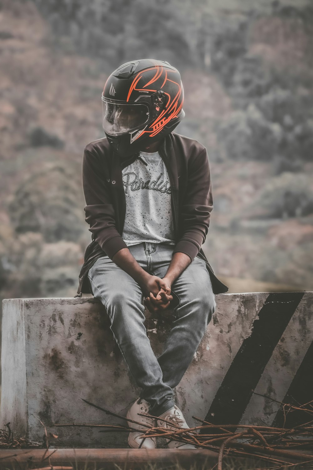 a man sitting on top of a cement block wearing a helmet