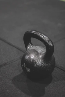 A sturdy kettlebell placed on a textured gym floor, highlighting its grip and weight markings.