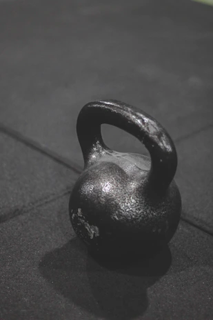 A sturdy kettlebell placed on a textured gym floor, highlighting its grip and weight markings.