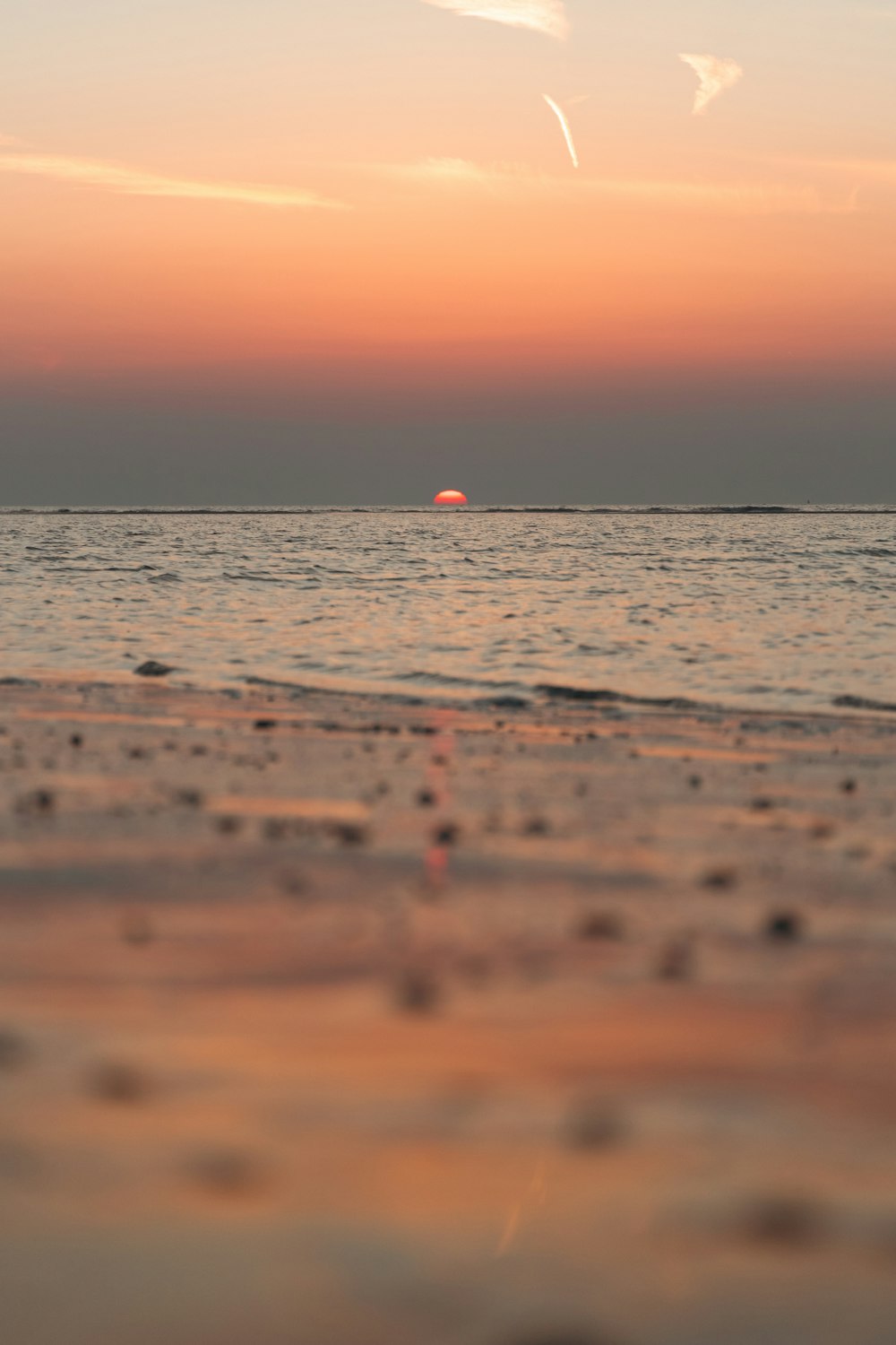 the sun is setting over the ocean on the beach