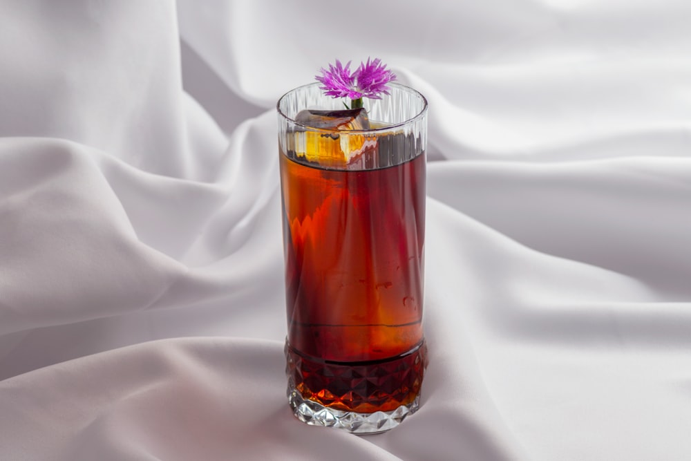 a glass of tea with a flower in it