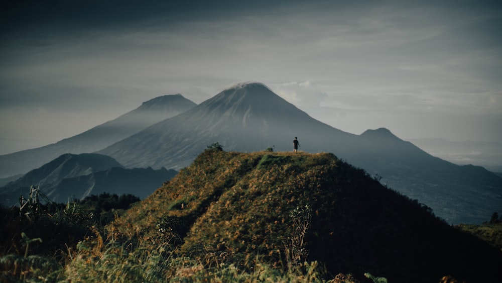 a person standing on top of a grass covered hill