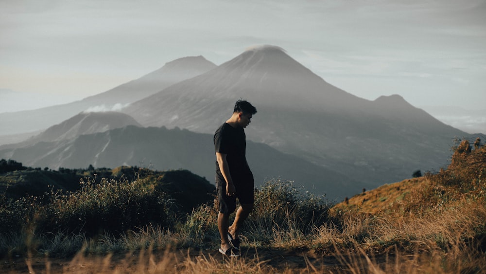 a man standing on top of a lush green hillside