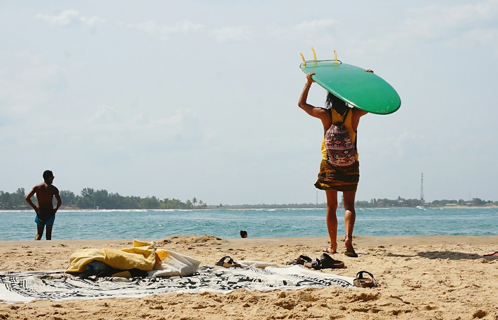 a woman carrying a surfboard over her head on a beach